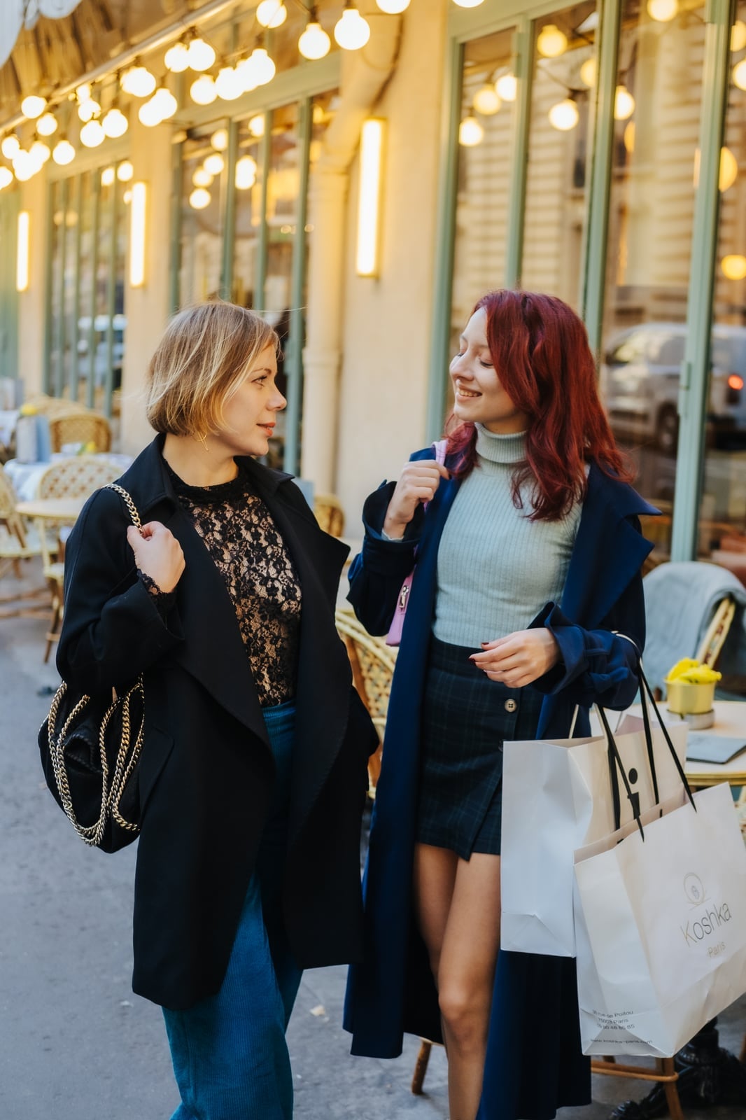 Clients in tailored coats walking past a Parisian café