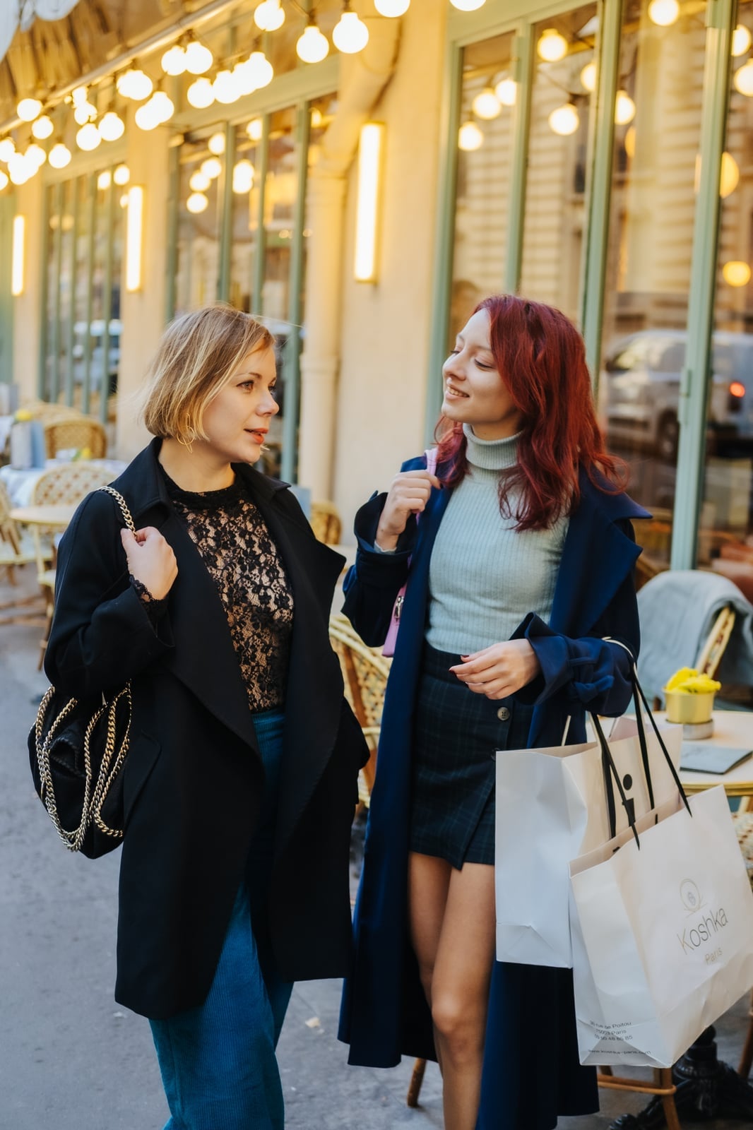 Two clients in tailored coats with shopping bags on a Paris boutique street