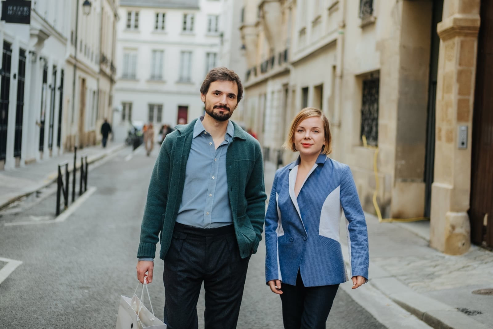 Couple walking through a quiet Paris street in tailored coats