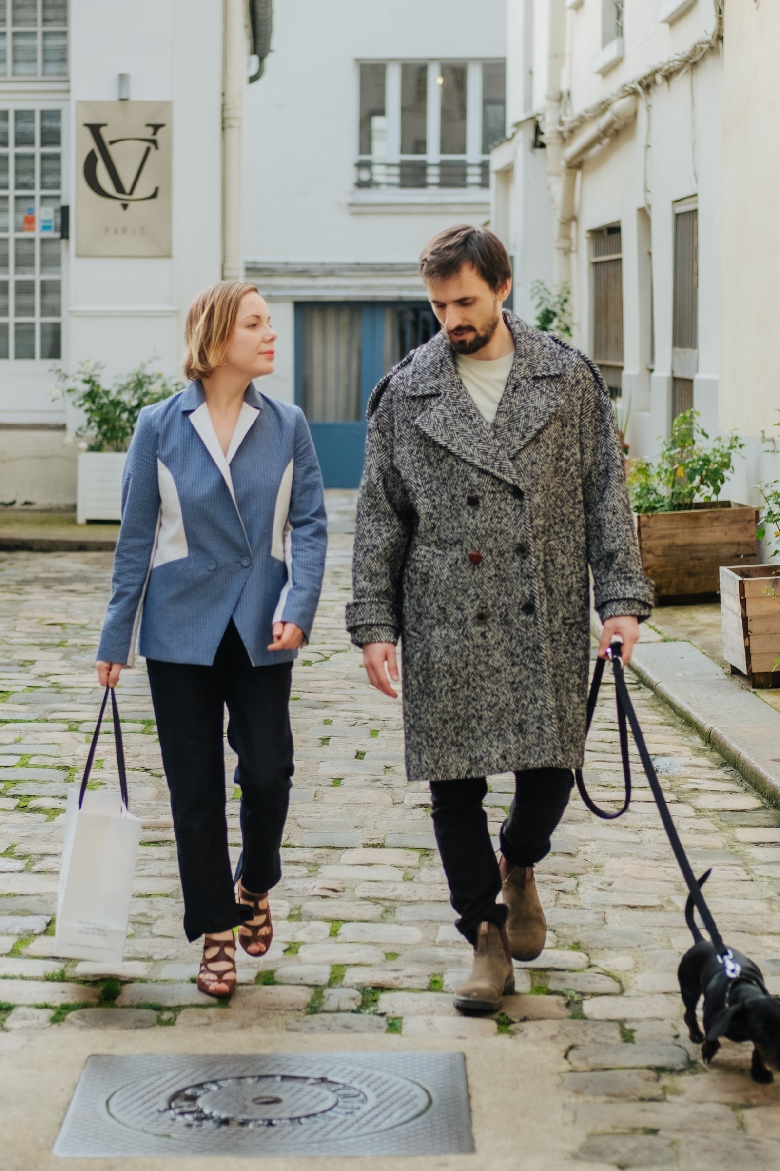Couple walking through a quiet Parisian courtyard with shopping bags